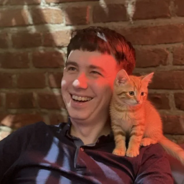 Nazar, co-founder and CTO of Outwarden, smiling, with a ginger kitten on his shoulder